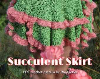 Puede incluir: Una falda de ganchillo verde con bordes de volantes rosas en capas. El texto en la imagen dice Succulent Skirt PDF crochet pattern by Rhosgobel. La falda tiene un patrón de puntos texturizado y una silueta acampanada con múltiples niveles.
