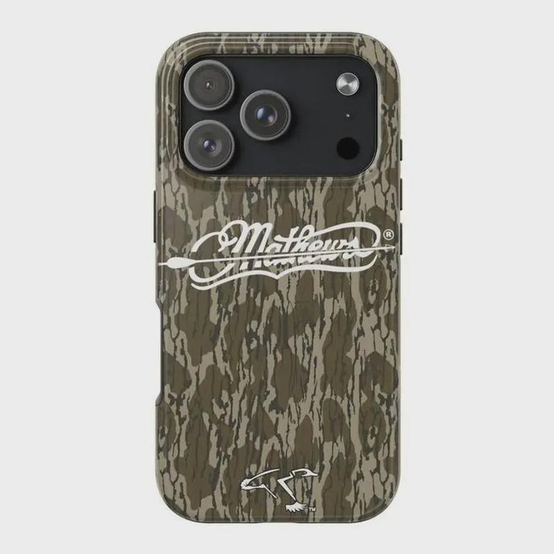 K&ouml;nnte beinhalten: Eine Handyh&uuml;lle mit Camouflage-Muster und drei Kameralinsen. Die H&uuml;lle hat den wei&szlig;en Text "Mathews" mit einem Pfeildesign und einem Entenlogo. Die H&uuml;lle dient zum Schutz des Telefons vor Besch&auml;digungen.