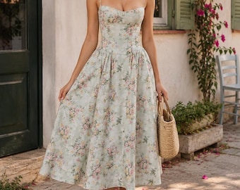 Könnte beinhalten: Ein wadenlanges Kleid mit hellgrünem Grund und einem zarten Blumenmuster in Rosa-, Gelb- und Grüntönen. Das Kleid hat ein eng anliegendes Oberteil mit dünnen Spaghettiträgern, einem herzförmigen Ausschnitt und einem weiten, plissierten Rock.