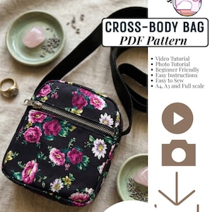 Op de afbeelding: Een zwarte schoudertas met een bloemenpatroon van roze rozen en witte madeliefjes. De tas heeft een voorvak met rits en een zwarte riem. Tekst bevat CROSS-BODY BAG PDF Pattern, Video Tutorial en INSTANT DOWNLOAD.