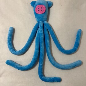 Peluche de calamar inspirado en Coraline: calamar azul con ojo de botón rosa. Disponible en 3 tallas (M/L). L