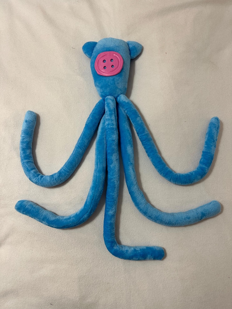 Peluche de calamar inspirado en Coraline: calamar azul con ojo de botón rosa. Disponible en 3 tallas (M/L). L
