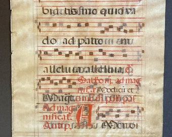 May include: A close-up of a page from a medieval manuscript with red and black ink. The page contains musical notation and Latin text. The text reads "miodameichoade bidatisfimo quidv do ad patron amu allclubvallсныг Datform, ad mag odicu et A Dugama.dipompar Admag nificat. Antiprabu спо".
