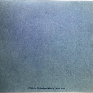 Op de afbeelding: Een blauw papieren boekje met de tekst "Published by The Boughton-Robbins Co., Spokane, Wash." onderaan.