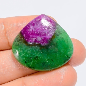 Peut inclure: Une pierre précieuse polie de forme arrondie en goutte d'eau. La partie supérieure est d'un magenta vif, passant à un vert profond à la base. La pierre a une surface lisse et brillante.