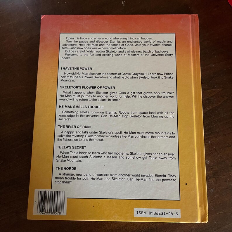 K&ouml;nnte beinhalten: R&uuml;ckseite eines Vintage-Geschichtenbuchs von Masters of the Universe. Das Cover ist gelb mit Text, der die Geschichten im Inneren beschreibt, darunter "I Have The Power" und "Teela's Secret". Das Buch hat einen Barcode und die ISBN 0932631-04-5.