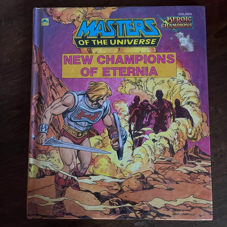 K&ouml;nnte beinhalten: Ein Vintage-Comicbuch "Masters of the Universe". Das Cover zeigt eine muskul&ouml;se Figur mit Schwert und Schild vor einer felsigen Landschaft und einer Gruppe von Silhouetten. Der Titel "New Champions of Eternia" ist deutlich sichtbar.