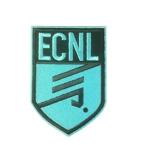 Op de afbeelding: Geborduurde patch met de letters "ECNL" in wit op een donkergroene achtergrond. Het onderste deel van de patch is lichtblauw met een zwart geometrisch ontwerp. De patch heeft de vorm van een schild.