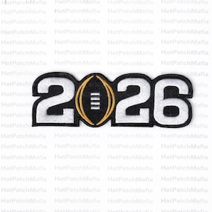 May include: Embroidered patch displaying the year "2026" in white, with a black border. A black football shape with gold trim and white stripes is in the centre. Suitable for application on clothing or accessories.