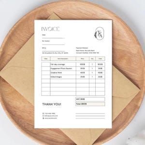 May include: A white invoice with black text, including "INVOICE" at the top and a breakdown of services. The invoice is on a wooden plate with a brown envelope. The invoice includes the text "THANK YOU!"