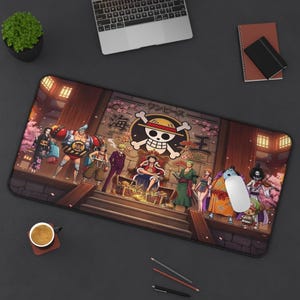 May include: A black rectangular mouse mat with a vibrant illustration of characters from the anime "One Piece." The design includes a skull and crossbones logo, Japanese text, and various figures in a detailed setting.