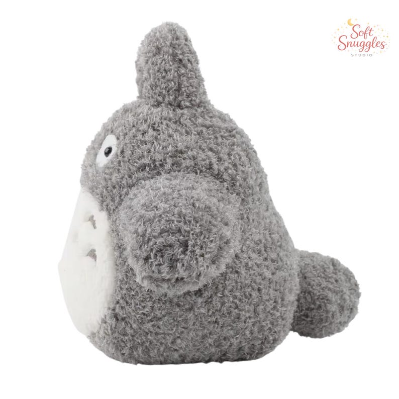 May include: A gray plush toy resembling a character from an animated film. The stuffed animal has a rounded body, small ears, and a white belly. The toy is made of soft, fuzzy material and has a friendly expression.