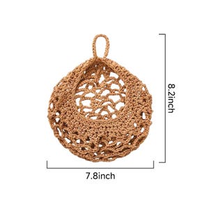 Puede incluir: Una cesta de almacenamiento colgante redonda, de color tostado, tejida a ganchillo con un patr&oacute;n de red de malla abierta y un lazo superior para colgar. El objeto muestra l&iacute;neas de medida que indican 20,8 cm de alto y 19,8 cm de ancho.