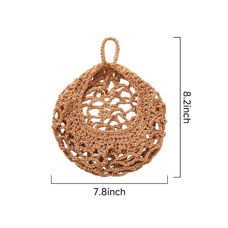 Puede incluir: Una cesta de almacenamiento colgante redonda, de color tostado, tejida a ganchillo con un patr&oacute;n de red de malla abierta y un lazo superior para colgar. El objeto muestra l&iacute;neas de medida que indican 20,8 cm de alto y 19,8 cm de ancho.