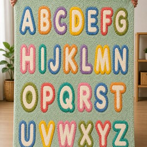 May include: A rectangular light green rug featuring the English alphabet in a tufted, bubble-letter style. Each letter is rendered in a distinct color, including blue, orange, purple, yellow, red, green, and pink, with a cream-colored center.