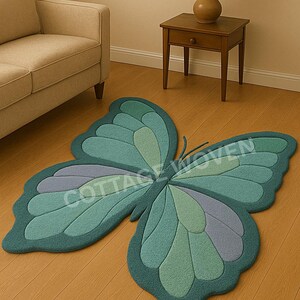 May include: A large, butterfly-shaped rug in shades of teal, green, and purple. The rug is made of a soft material and has a textured appearance. The text "COTTAGE WOVEN" is visible on the rug.