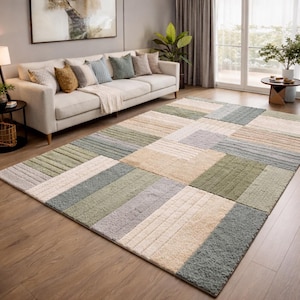 Peut inclure: Un grand tapis rectangulaire avec un motif patchwork. Le tapis présente une variété de formes rectangulaires et carrées dans des tons de vert, beige, gris et blanc. Le tapis est posé sur un parquet dans un salon.