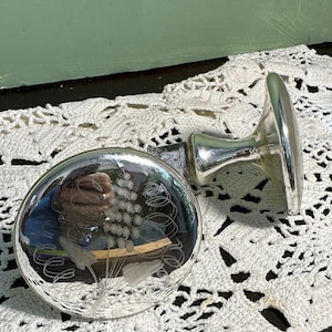 May include: Two silver-toned glass bottle stoppers with a floral design etched into the glass. The stoppers are round and have a flat base.