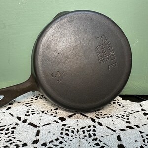 May include: A black cast iron skillet with a handle. The skillet is labeled "Favorite Flour Ware" and "3A".