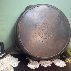 May include: A cast iron Griswold skillet with the text "Griswold Cast Iron Skillet" and "U.S.A." on the bottom. The skillet is in good condition with some signs of wear.