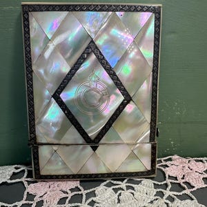 May include: A white ceramic mug with a black handle and the text "But First, Coffee" in a bold, black font. The mug is set against a blurred background, highlighting its simple design.