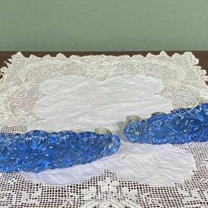 Puede incluir: Dos tiradores de cajón de vidrio azul con un diseño floral. Los tiradores son de vidrio y tienen un respaldo de metal plateado.