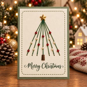 May include: A rectangular greeting card with a cream-colored center panel featuring a stitched border. A stylized Christmas tree is formed by green thread, red and white beads, and a gold star topper. The text Merry Christmas is printed below.
