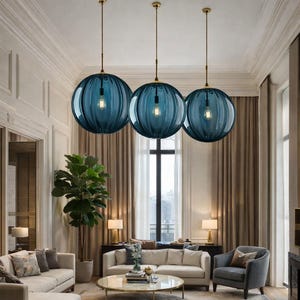 May include: Three pendant lights with spherical, ribbed, teal-colored glass shades hang from the ceiling. Each light has a visible bulb and is suspended by a gold-colored cord. The lights are in a living room setting.