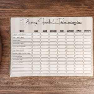 May include: A rectangular family chore planner board with a beige and white striped background. The header reads Planning Familial - T&acirc;ches m&eacute;nag&egrave;res. It features a grid with columns for days of the week and rows for household tasks.