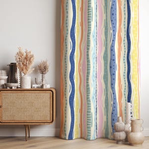 May include: A patterned curtain with vertical stripes in blue, yellow, orange, pink, and green. The design incorporates wavy lines and dotted patterns, creating a vibrant and artistic appearance. The curtain is likely made of fabric and adds a decorative element to a room.