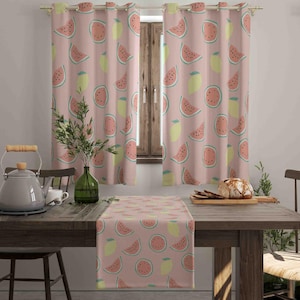 Pode incluir: Um par de cortinas rosa claro e um caminho de mesa a condizer com um padrão repetitivo de fatias de melancia e limões amarelos. As cortinas estão penduradas num varão de metal e o caminho de mesa está estendido numa mesa de madeira.