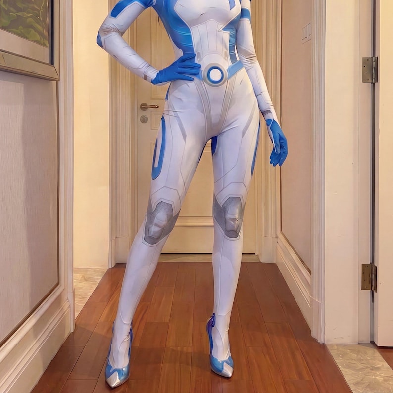 May include: A full-body white and blue spandex bodysuit featuring a futuristic printed design with geometric paneling, a circular waist emblem, and matching blue gloves. The suit includes integrated foot coverings with pointed metallic-toned toes.