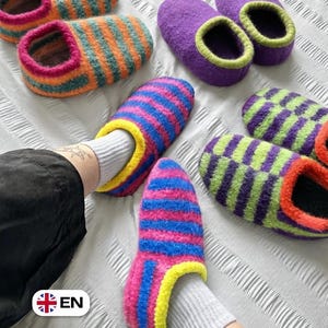 May include: A collection of felted wool slippers in various colour combinations. One pair features orange and teal stripes with pink trim, another is solid purple with lime green trim, and a third pair has blue and pink stripes with yellow trim.