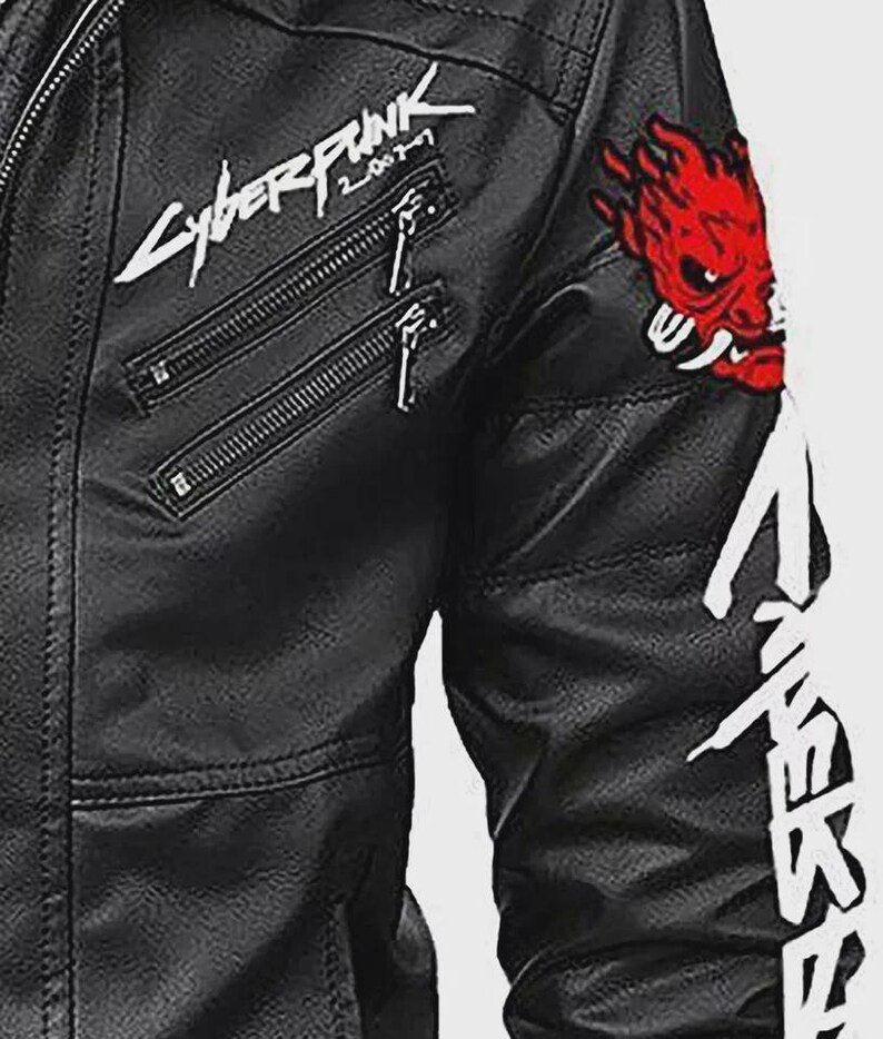Może przedstawiać: Czarna kurtka ze sztucznej sk&oacute;ry z wieloma kieszeniami zapinanymi na zamek i białym napisem "Cyberpunk 2077". Posiada czerwoną naszywkę z demonem na rękawie i biały tekst wzdłuż ramienia. Kurtka ma klasyczny styl motocyklowy.