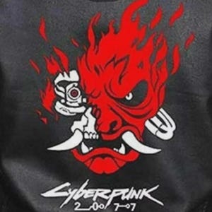 Może przedstawiać: Czarna kurtka z czerwono-białą grafiką stylizowanej twarzy demona z płomieniami. Tekst "Cyberpunk 2077" jest wydrukowany poniżej na biało, z numerami "2007" i "707".