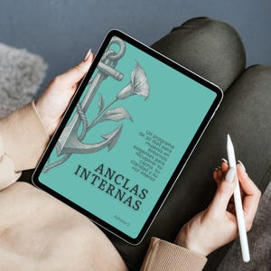 May include: A tablet displaying a teal cover with the title "ANCLAS INTERNAS" and an illustration of an anchor and flowers. The text on the cover is in Spanish. A white stylus rests on the person's lap.