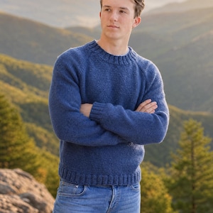 Peut inclure: Un pull à manches longues et col rond d'une couleur bleu moyen unie, doté d'un motif en tricot côtelé au niveau du col, des poignets et de l'ourlet, associé à un jean bleu clair. Le vêtement présente une texture tricotée et une coupe standard.