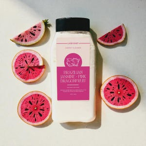 May include: A white bottle of Lucid Coast carpet cleaner with a black cap, surrounded by sliced pink dragonfruit. The label reads "Brazilian Jasmine Pink Dragonfruit". The dragonfruit slices are arranged around the bottle.
