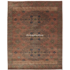 May include: A rectangular area rug in shades of terracotta, rust, and muted green. The rug features a central repeating geometric medallion pattern with floral motifs and a wide decorative border. The text Heritageknotloom is centered on the rug.