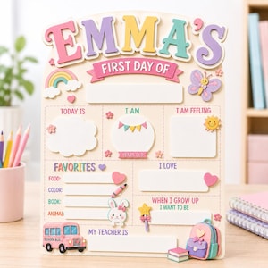 May include: A wooden first day of school sign featuring the name EMMA'S in colorful 3D letters. The board includes sections for today's date, age, feelings, favorites, and future goals, decorated with a rainbow, butterfly, school bus, and backpack.