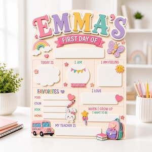 May include: A wooden first day of school sign featuring the name EMMA'S in colorful letters. The board includes sections for Today Is, I Am, I Am Feeling, Favorites, I Love, When I Grow Up I Want To Be, and My Teacher Is, decorated with a rainbow, butterfly, school bus, and backpack.