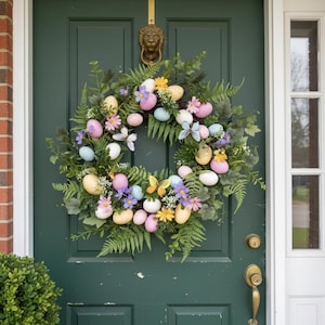 May include: An Easter wreath with colourful eggs, butterflies, and flowers. The wreath is made of greenery and is displayed on a green door. The wreath features pastel-coloured eggs in pink, yellow, and blue.