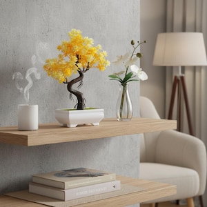 May include: A decorative bonsai tree with yellow leaves in a white rectangular pot sits on a wooden shelf. A small glass vase with white flowers and a white candle are also on the shelf. The scene is set in a living room.