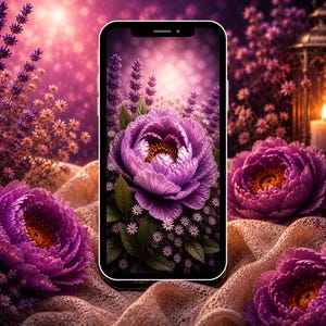 Op de afbeelding: Een smartphone toont een digitale afbeelding van een grote paarse pioenroos, omringd door lavendel en kleine witte bloemen. De achtergrond is een zacht, wazig roze met bokeh-effecten. De scène is geplaatst op een getextureerd, beige oppervlak.
