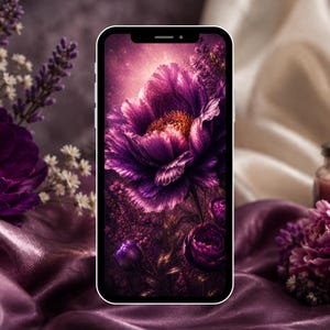 Op de afbeelding: Een smartphone toont een digitale bloemenafbeelding van een grote, levendige paarse bloem met een gouden centrum. De telefoon ligt op paars satijn, omringd door verse bloemen en een brandende kaars.