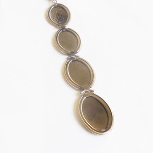 Puede incluir: Un collar de cadena de plata con un colgante de medall&oacute;n. El medall&oacute;n tiene cuatro compartimentos ovalados que se abren para revelar espacios vac&iacute;os para fotos o recuerdos.