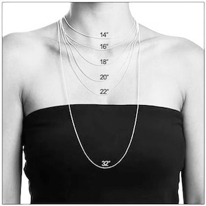 Puede incluir: Una modelo lleva un collar de cadena de plata en varias longitudes, incluyendo 14 pulgadas, 16 pulgadas, 18 pulgadas, 20 pulgadas, 22 pulgadas y 32 pulgadas. El collar se muestra sobre un fondo negro.