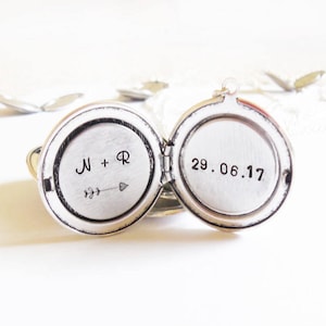 May include: Silver locket necklace with two engraved sides. One side reads "N + R" with an arrow and the other side reads "29.06.17".
