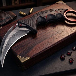 May include: A karambit knife with a curved blade, black handle, and red accents rests on a wooden box with brass corner protectors. A leather sheath, bullets, and a compass are also visible, suggesting a tactical or survival theme.