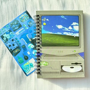 May include: A spiral-bound notebook featuring a retro computer illustration with a green landscape screen, paired with a blue sticker sheet displaying various small icons, gadgets, and digital objects in a cohesive, vibrant, and detailed graphic style.